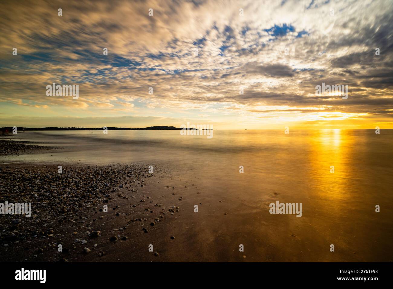 Una lunga pausa al tramonto su una spiaggia mediterranea, il movimento dell'acqua, l'ora d'oro e il paesaggio ispirano tranquillità e pienezza Foto Stock
