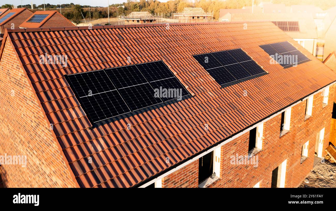 Il tetto di una fila di case di nuova costruzione in un cantiere con tetto integrato o pannelli solari a tetto per un'energia economica e sostenibile in un ambiente ecologico Foto Stock