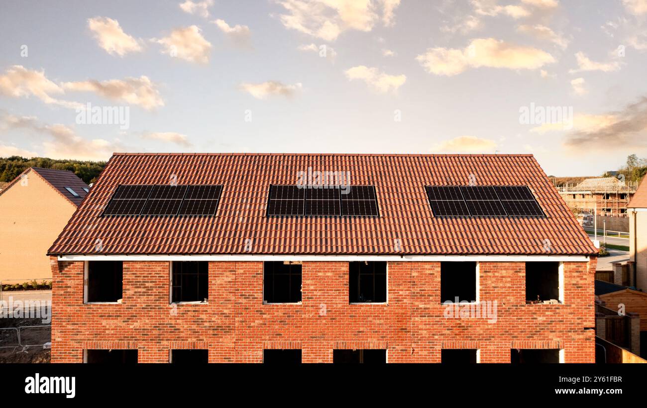 Il tetto di una fila di case di nuova costruzione in un cantiere con tetto integrato o pannelli solari a tetto per un'energia economica e sostenibile in un ambiente ecologico Foto Stock