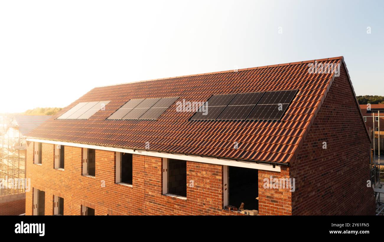 Il tetto di una fila di case di nuova costruzione in un cantiere con tetto integrato o pannelli solari a tetto per un'energia economica e sostenibile in un ambiente ecologico Foto Stock