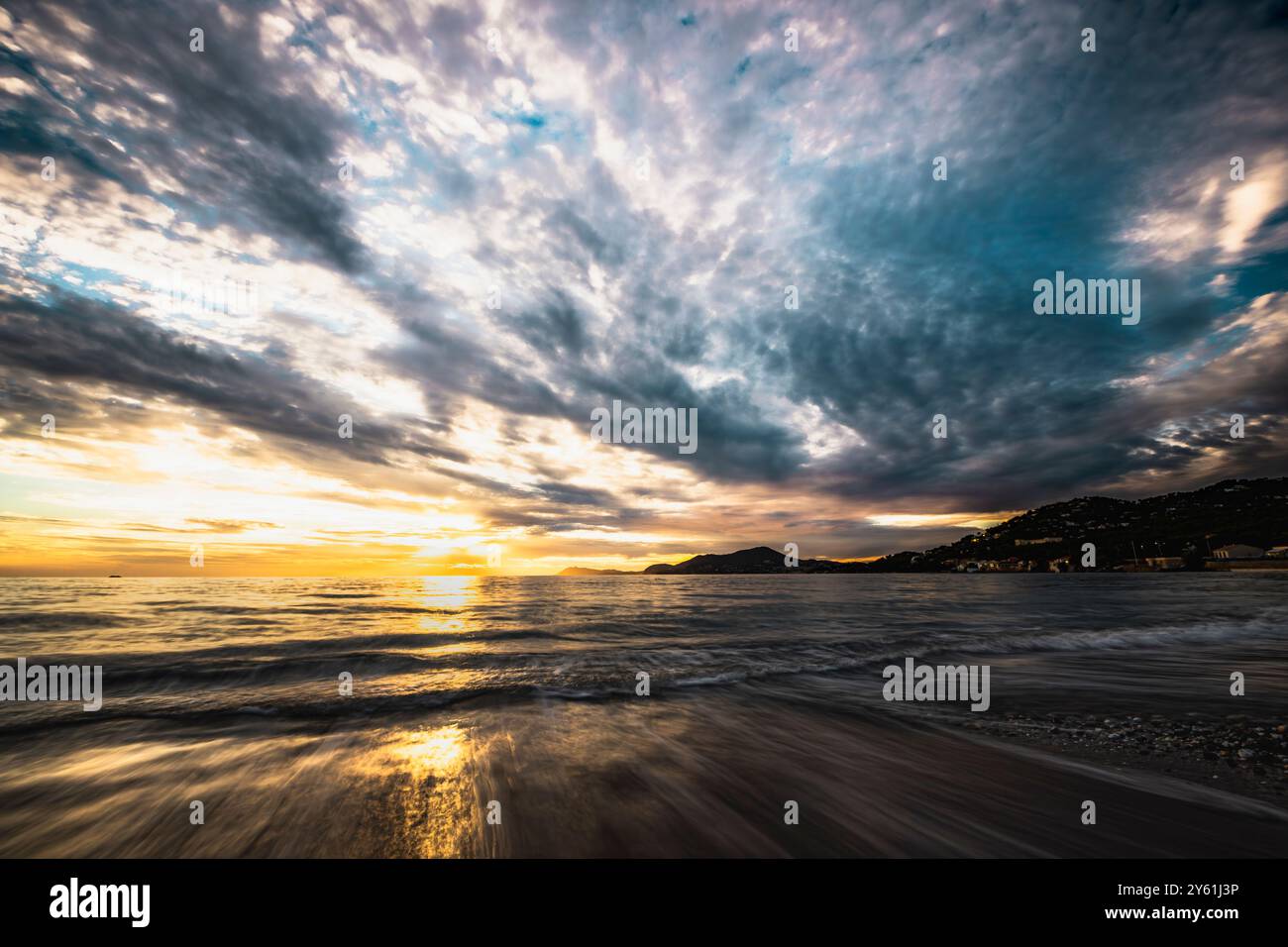 Una lunga pausa al tramonto su una spiaggia mediterranea, il movimento dell'acqua, l'ora d'oro e il paesaggio ispirano tranquillità e pienezza Foto Stock