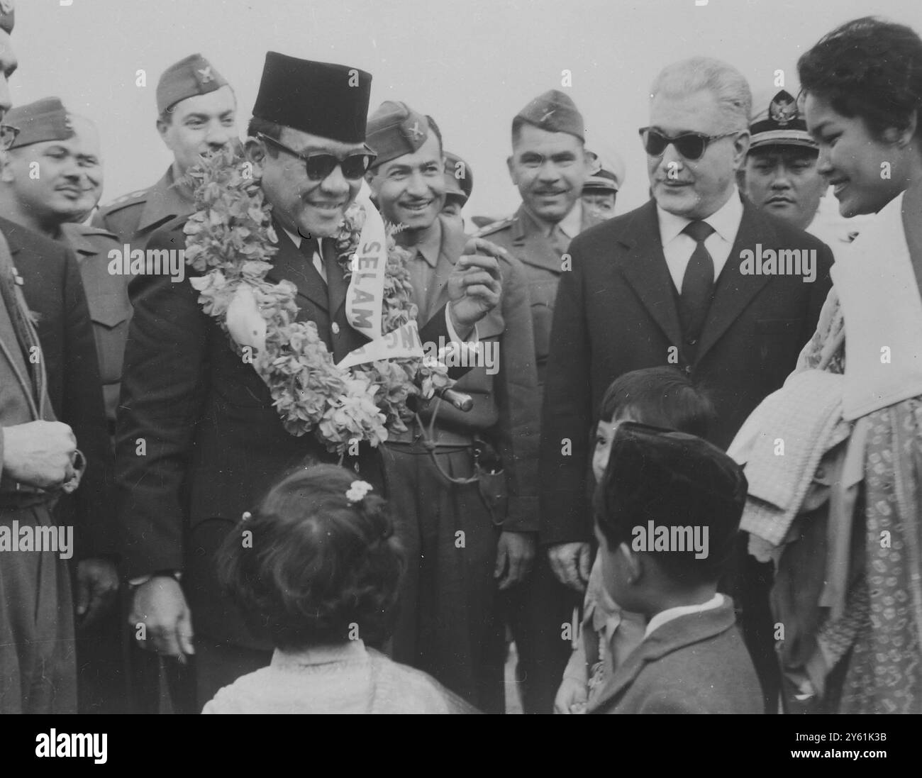 GLI SCOLARI IRACHENI AVVOLGONO UNA GHIRLANDA DI PISELLI DOLCI INTORNO AL COLLO DEL PRESIDENTE AHMED SUKARNO 4 APRILE 1960 Foto Stock