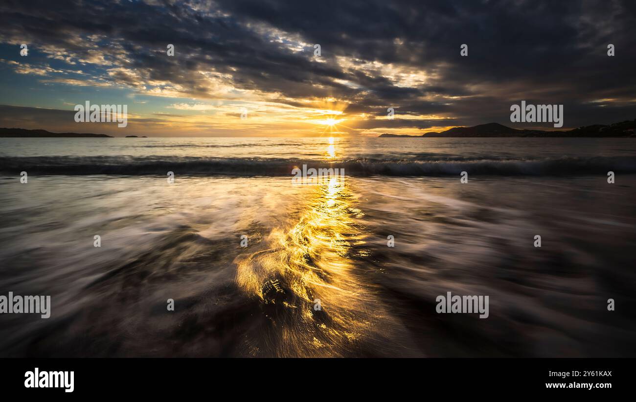 Una lunga pausa al tramonto su una spiaggia mediterranea, il movimento dell'acqua, l'ora d'oro e il paesaggio ispirano tranquillità e pienezza Foto Stock