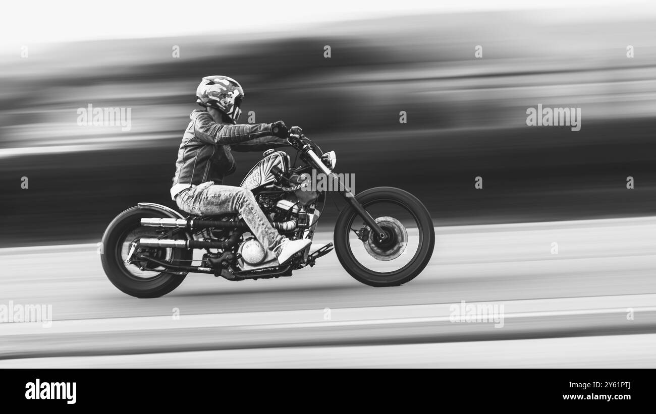 un motociclista si precipita lungo una strada durante il suo viaggio Foto Stock