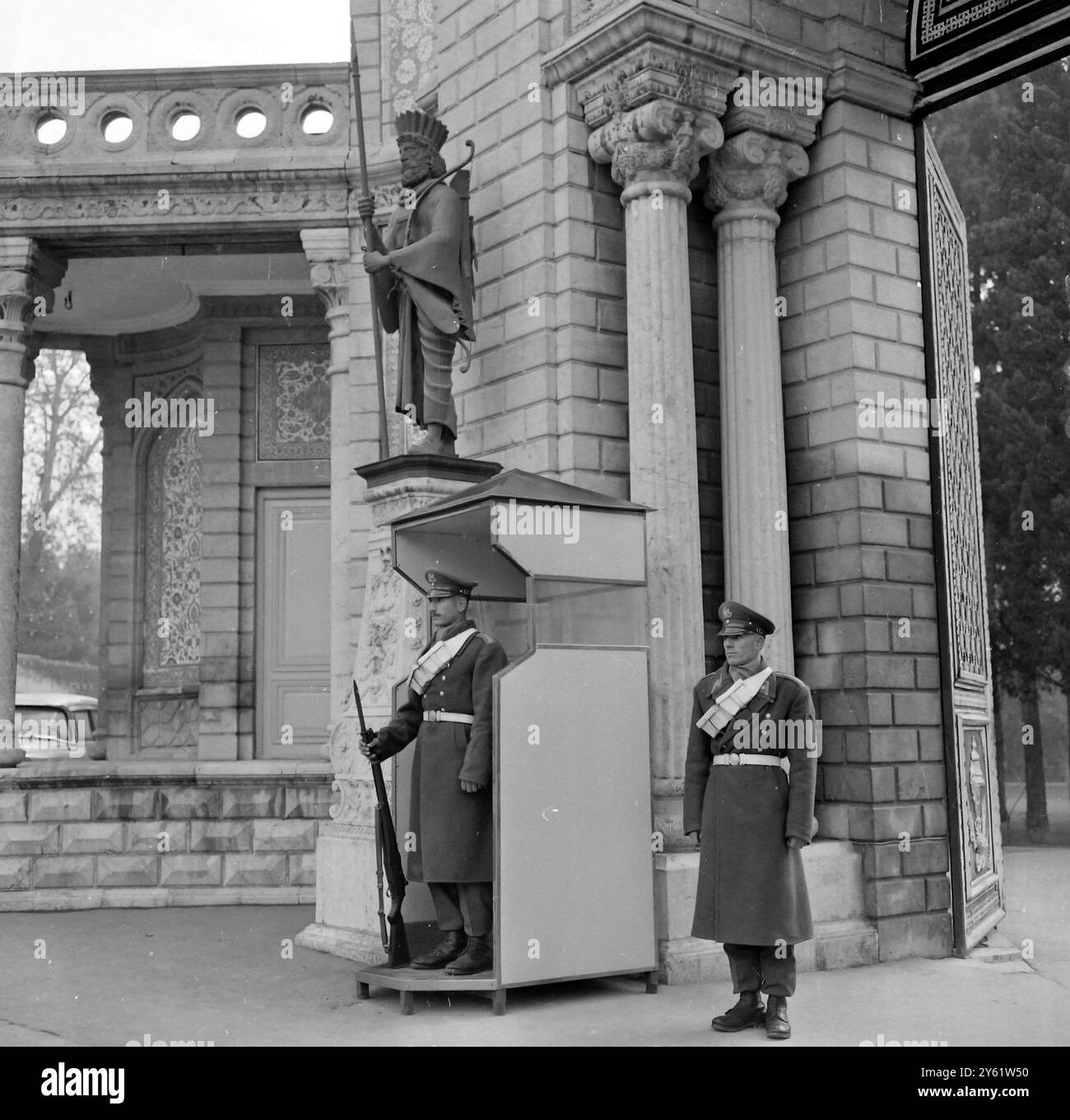 GUARDIE REALI ALL'ESTERNO DEL PALAZZO DI MARMO NELLA CITTÀ DI TEHERAN IN IRAN CHE MOSTRA UNA STATUA DI ANTICO GUERRIERO DI ARCO E FRECCIA SOPRA IL 9 FEBBRAIO 1960 Foto Stock