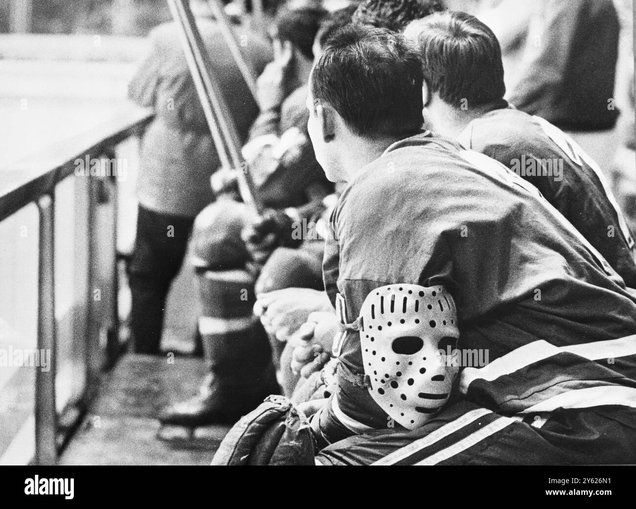 Un Masked questa non è una nuova moda amonig sportivi, e se la sua maschera protettiva gli fa perdere gli occhi vuoti, il portiere della riserva cecoslovacca Vladimir Nadrchal guarda con profondo interesse mentre i suoi compagni di squadra forniscono una vittoria sconvolta contro la squadra finora imbattuta dell'URSS durante la partita di hockey su ghiaccio allo stadio Grenoble Ice. La maschera posta sul braccio del portiere è quasi un must per il portiere dell'hockey su ghiaccio per proteggere il viso dai dischi rigidi di ferro che viaggiano ad alta velocità 17 febbraio 1968 Foto Stock