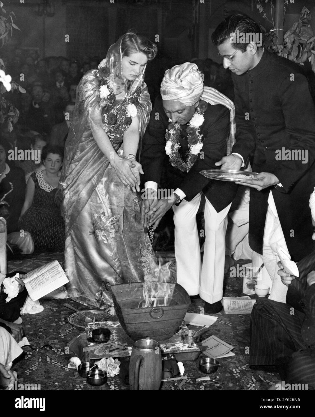 La sposa rivestita di sari , l'infermiera irlandese Miss Sadie Durkin , e lo sposo turbato , il proprietario del ristorante Mr. Shri Dharam Chand Wadhwa , hanno gettato incenso sul fuoco al loro matrimonio , con cerimonie indù , nelle sale Mayfair a Marylebone , Londra . La cerimonia è stata eseguita presso l'altare di un tempio indù di imitazione costruito nelle loro stanze il .26 settembre 1954 Foto Stock