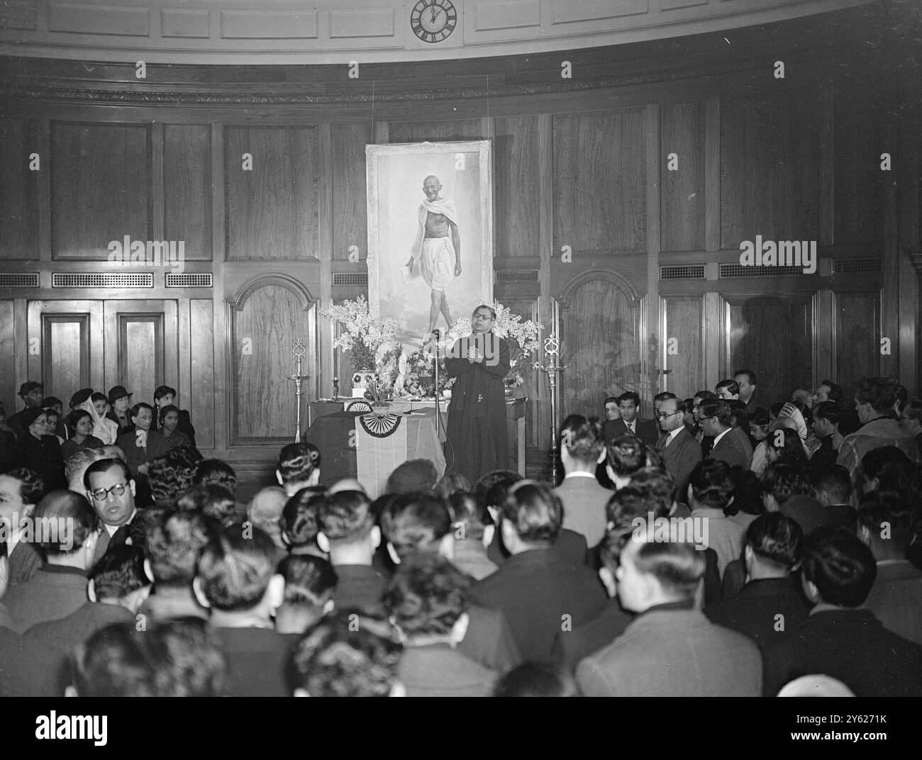Centinaia di piangenti per il Mahatma Gandhi hanno sentito M. Khrishna Menon, alto Commissario per il dominio dell'India, rendere omaggio al leader assassinato oggi, alla India House. L'incontro si svolse nella biblioteca prima dell'immagine del Mahatma, e trasmesso da apparecchiature audio a coloro che non erano in grado di entrare nella stanza. Immagini: Una vista della ricca biblioteca di India House, mentre il Dr. Hari Prasad, un prete indiano, parla in lode del Mahatma. 31 gennaio 1948 Foto Stock