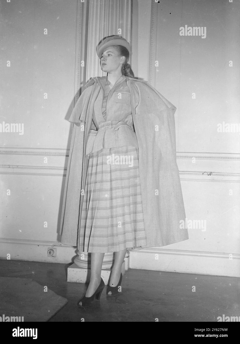 Questo elegante e informale pezzo a tre chiamato "Avenue de Bois" attende con ansia la primavera. Realizzata in lana, grigia per la giacca e il cappotto lungo in stile mantello e grigia a righe incrociate con rosa e marrone per la gonna, la tuta è caratterizzata dal "look londinese", una gonna decisamente più lunga di quella precedente all'era Christian Dior, ma non fino a quando Parigi potrebbe richiedere. 27 gennaio 1948 Foto Stock