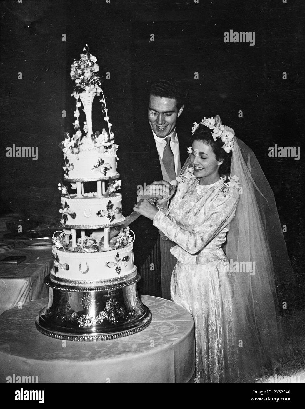 La nuova star britannica Kieron Moore - "The Man About the House" - si è sposata a St Patrick's Soho Square, con l'attrice Barbara White. Sia la sposa che lo sposo hanno 23 anni. Le immagini mostrano: "Tagliare in armonia" la felice coppia nuziale si unisce per tagliare la magnifica torta nuziale al ricevimento del Savoy Hotel. 4 dicembre 1947 Foto Stock
