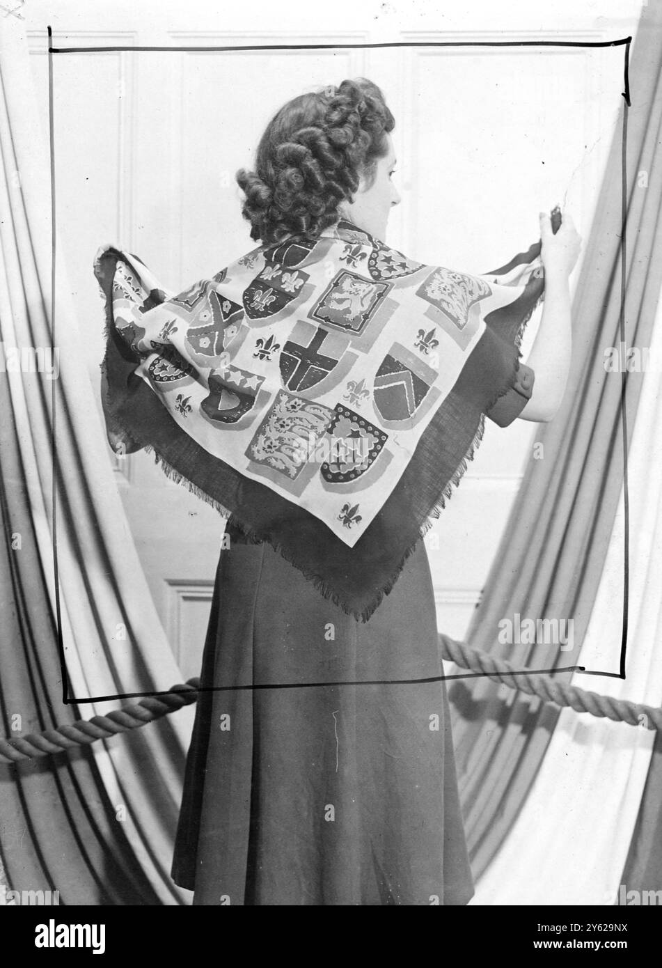 Gli agenti di 185 case di moda d'oltremare vedranno la nuova collezione di abiti e tessuti d'arredo creata da Halle's (oltreoceano) Ltd La nuova mostra, ora in vista a Londra, include disegni e colorazioni che riproducono l'esotica atmosfera orientale, mentre i prezzi variano da pochi scellini per iarda fino a 14 e 15 scellini per iarda per le sete di Macclesfield. Le immagini mostrano: Questa combinazione di colori eccezionalmente bella raffigurante una serie di creste araldiche su terreni pianeggianti, forma una sciarpa "Old Glory" per il modello alla mostra dei tessuti di Halle oggi. 8 dicembre 1947 Foto Stock