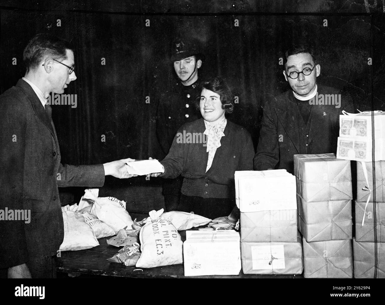 Una "scatola di Natale" di 85.000 sterline è stata prelevata oggi dalla banca di Hammersmith per la quota di Natale delle società congregazionali di Broadway. Spettacoli fotografici: Il presidente, Rev. Wallace Hayward (a destra) che supervisiona la distribuzione delle 85.000 sterline per l'inserimento in pacchetti, alla Broadway Congregational Hall, Hammersmith. 11 dicembre 1947 Foto Stock