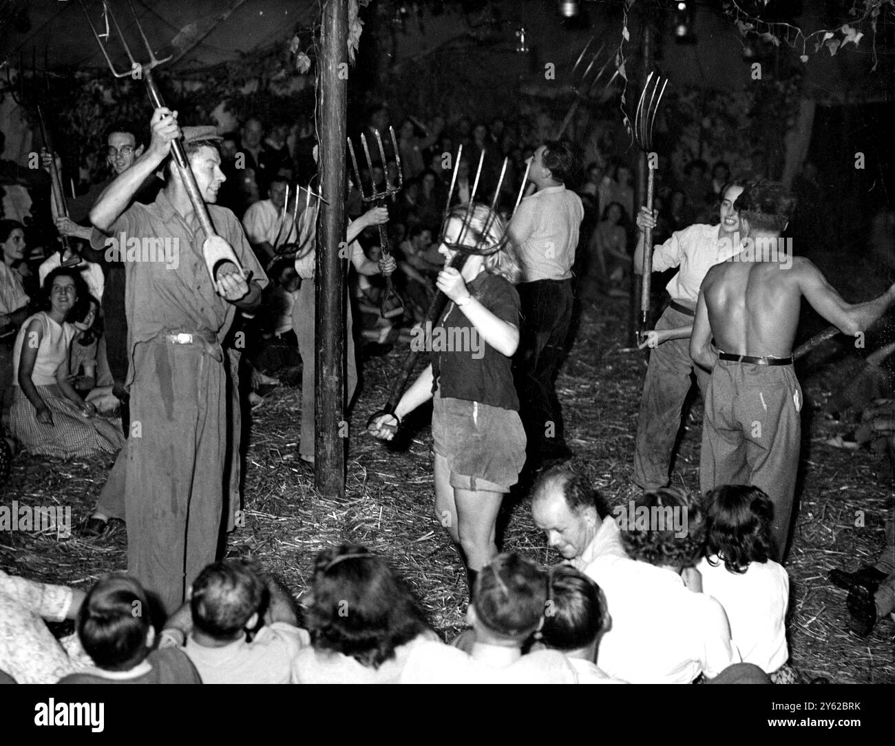 Le forchette allevate, la gente che ha combattuto la battaglia dei raccolti stanno festeggiando ora, calpestando la paglia nella danza tradizionale in una delle più grandi case di raccolto della Gran Bretagna. Intorno ai ballerini nel tendone sul pascolo di High Halden, villaggio del Kent di 500 anni, 300 giovani cittadini si mescolano con la gente del paese. Gli abitanti della città che hanno risposto alla chiamata alla terra sono tornati alla Turk's Head Farm dell'associazione ostello Yough, facendo merrificazione tra gli agricoltori che hanno aiutato. Il raccolto è stato buono quest'anno. Si prevede ufficialmente che il frumento raggiunga una media di quasi una tonnellata all'acro, ovvero tre quarti di A. Foto Stock