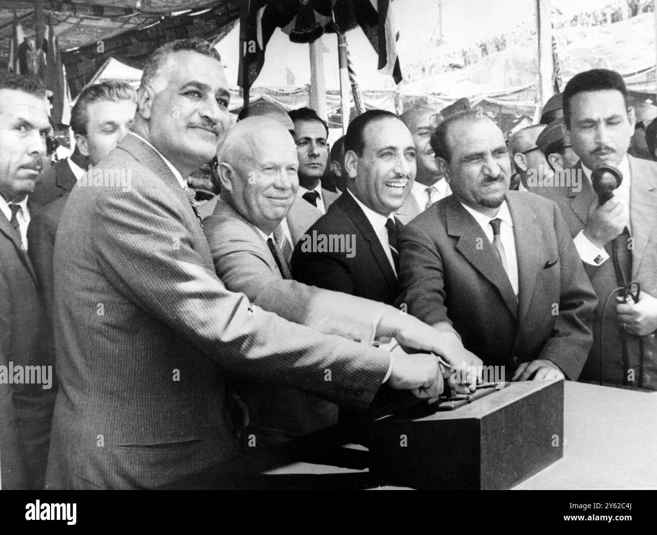 14 MAGGIO 1964 quattro dita famose premere il pulsante. Da sinistra a destra qui oggi ci sono il Presidente Gamal Abdel Nasser dell'UAR in visita al Premier sovietico Nikita Khruschev, al Presidente iracheno Aref e al Presidente Sallal dello Yemen, a cui viene mostrato di premere un pulsante che ha innescato una carica esplosiva che ha fatto esplodere una barriera sonora e ha deviato il fiume Nilo verso est attraverso sei enormi tunnel, in questo sito della Diga di Assuan. In seguito, una seconda esplosione fu scatenata dagli ingegneri all'estremità del tunnel per riportare l'acqua deviata al suo vecchio canale sotto il sito della diga. La cerimonia di oggi Foto Stock