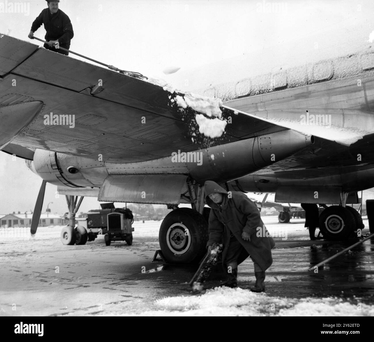 Il lavoratore aeroportuale , presso l' aeroporto di Londra , che pulisce la neve da un aereo Hermes , sta per ricevere una valanga da una delle ali . Gennaio 1951 Foto Stock
