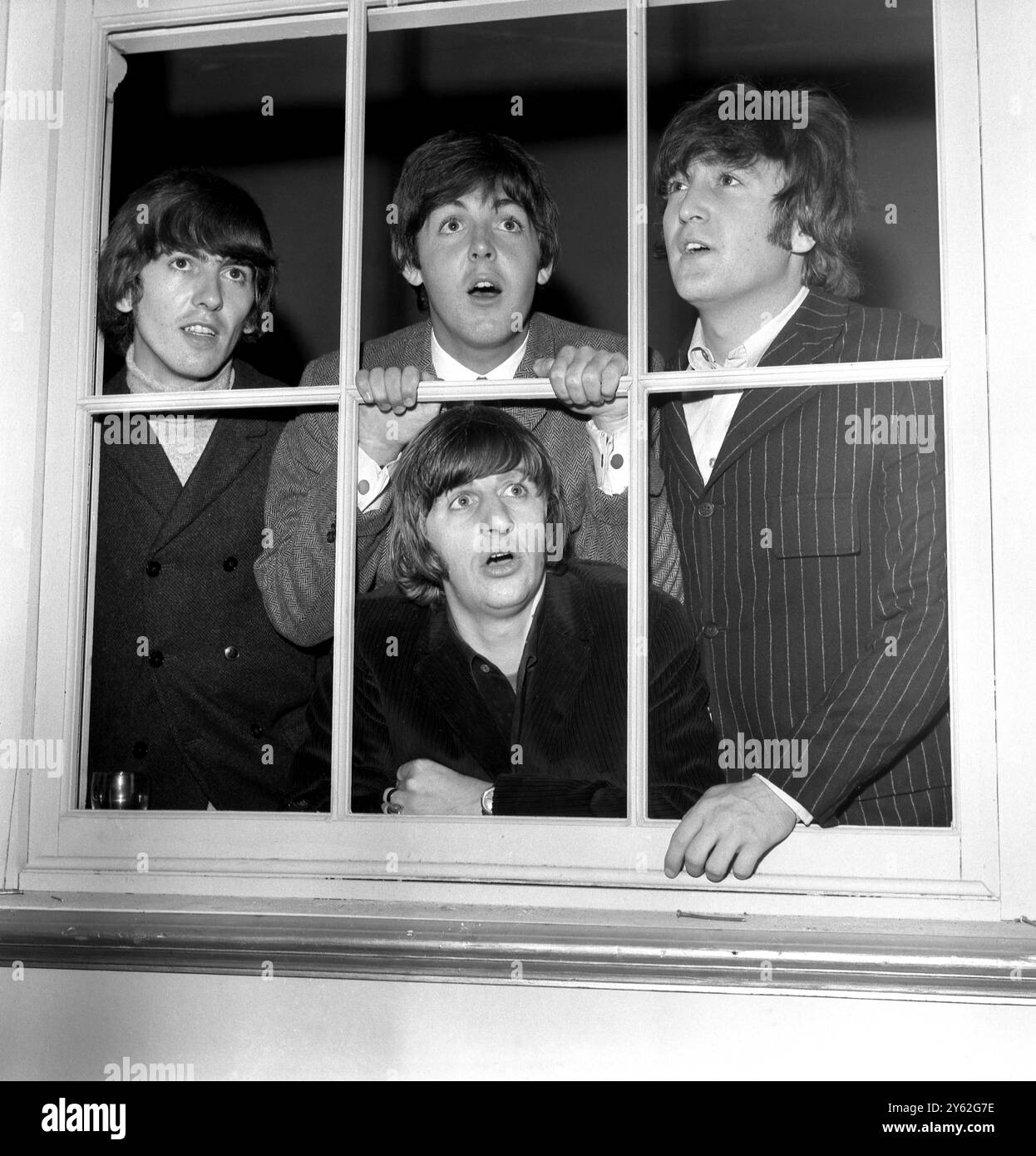 I Beatles - da sinistra a destra - George Harrison , Paul McCartney e John Lennon con Ringo Starr che guarda attraverso la finestra in basso ai Twickenham Studios . 12 giugno 1965 Foto Stock