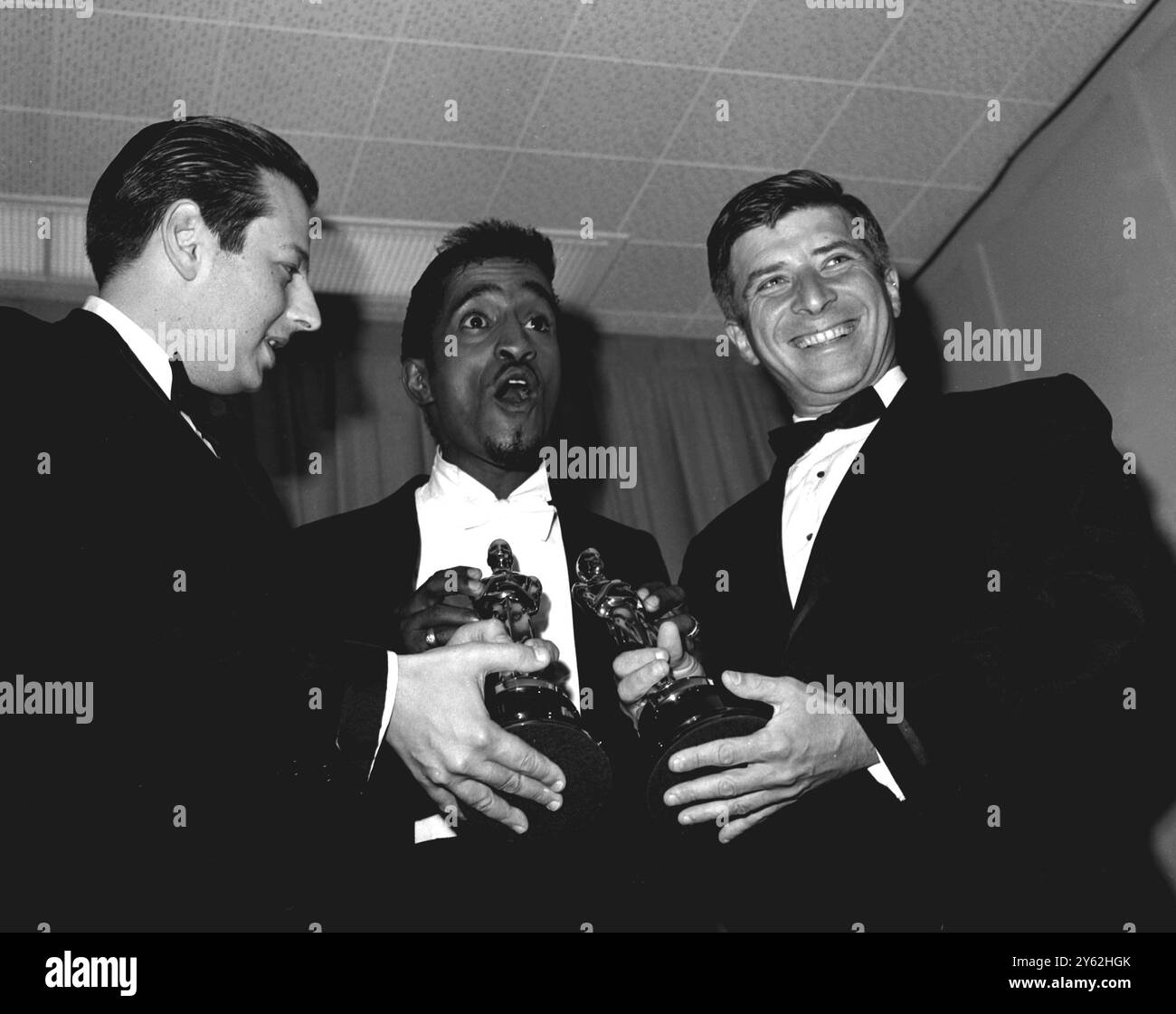Sammy Davis Jnr sembra che abbia la bavaglio appropriata mentre posa qui con il pianista compositore Andre Previn a sinistra e Elmer Berstein a destra. Alla presentazione annuale degli Academy Awards. Previn ha vinto un Oscar per la colonna sonora mentre Bernstein ha raccolto un Oscar per conto di John Addison per il film Tom Jones ha ricevuto il premio per la migliore colonna sonora sostanzialmente originale Santa Monica California 16 aprile 1964 Foto Stock