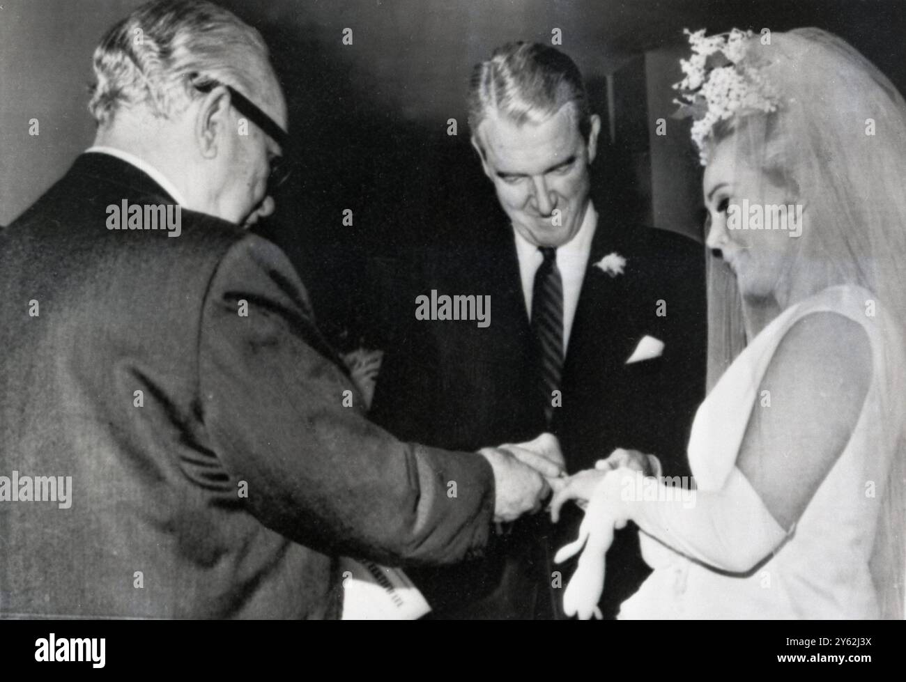 Zsa Zsa Gabor ottiene il quinto anello nuziale della sua carriera scivolato al dito dal ricco petroliere texano Joshua S Cosden . Il giudice Edward R Brand (a sinistra) ha officiato . 10 marzo 1966 Foto Stock