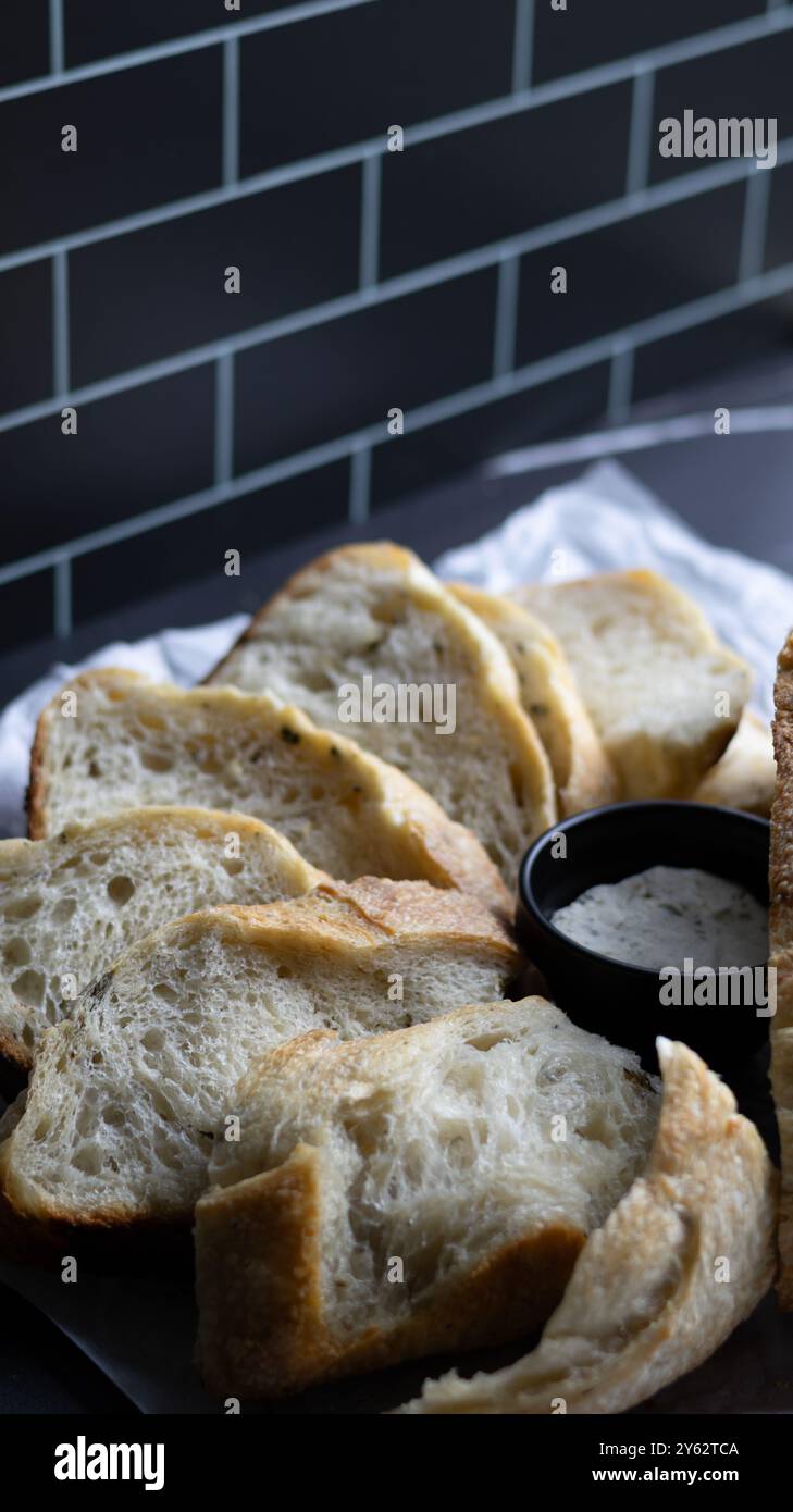 Primo piano di un pane rustico a fette di lievito madre alle erbe con formaggio spalmabile alle erbe. Ottimo per blog di cibo, libri di cucina, siti web e ristoranti Foto Stock