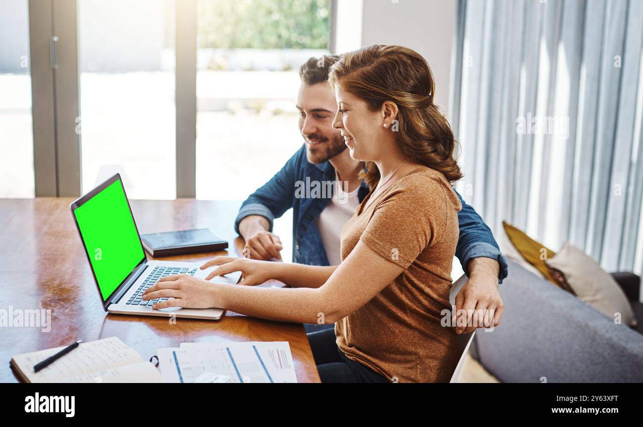 Chiave Chroma, accoppiata e felice con un notebook a casa per investimenti ipotecari, risparmi di budget o documenti cartacei. Persone, schermo verde e sorrisi al tavolo da pranzo Foto Stock