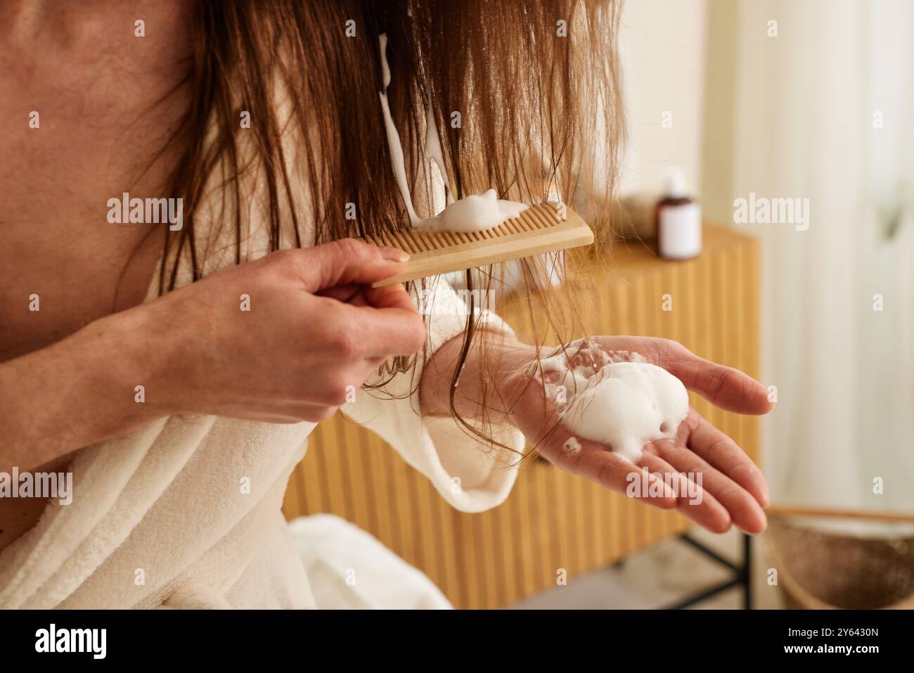 uomo che applica prodotti per la cura dei capelli con pettine in bagno. problemi di capelli Foto Stock
