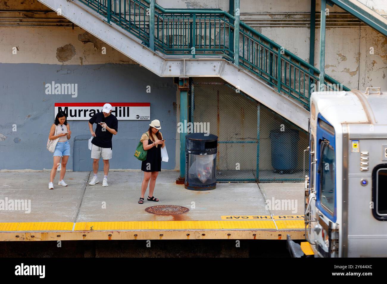 Coreani americani, asiatici americani in attesa di un treno in arrivo alla stazione di Murray Hill della Long Island Rail Road, New York City. Foto Stock