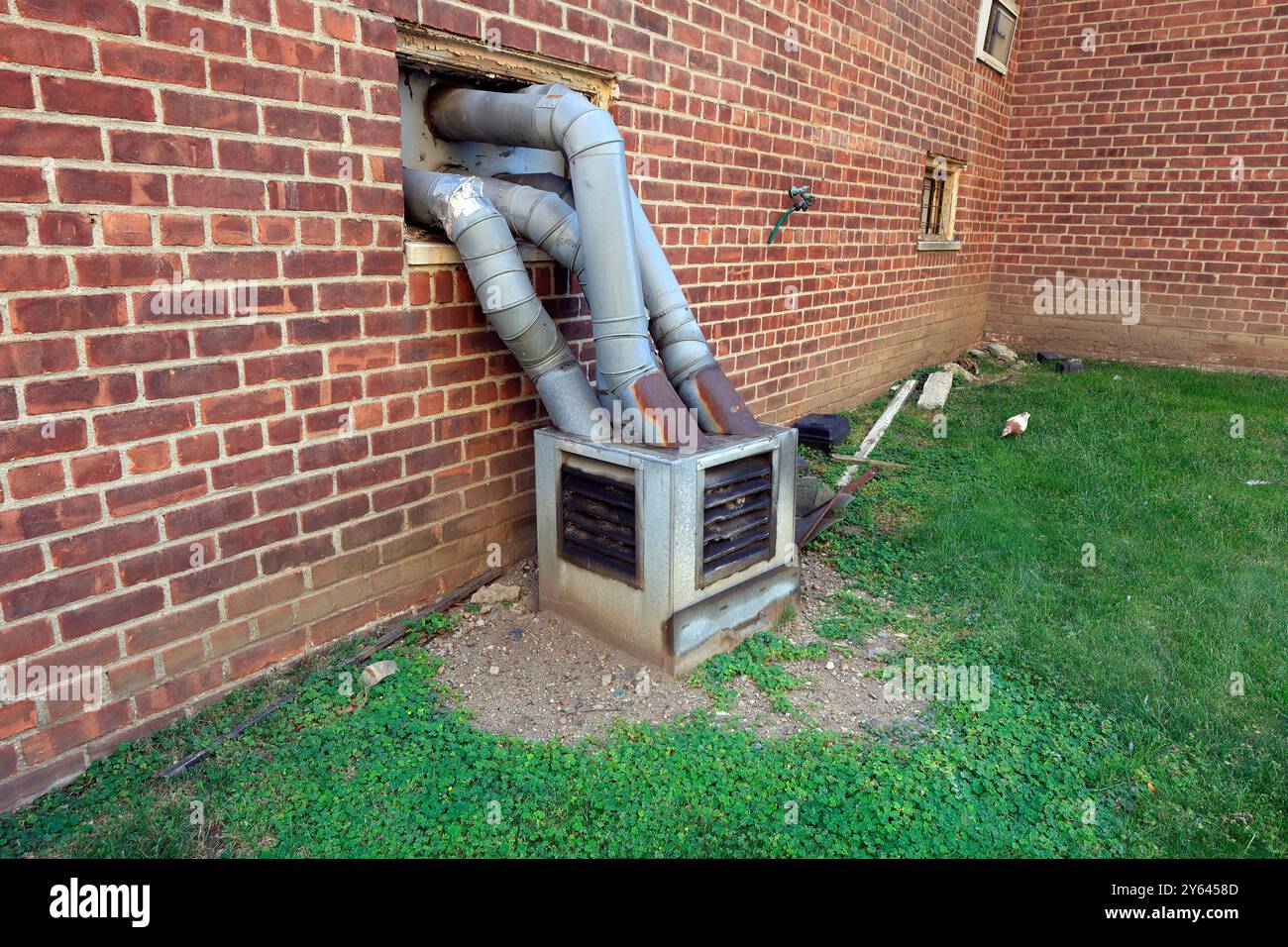 Quattro tubi di sfiato hvac per asciugatrici da bucato entrano in un piccolo trappola per pelucchi all'aperto Foto Stock