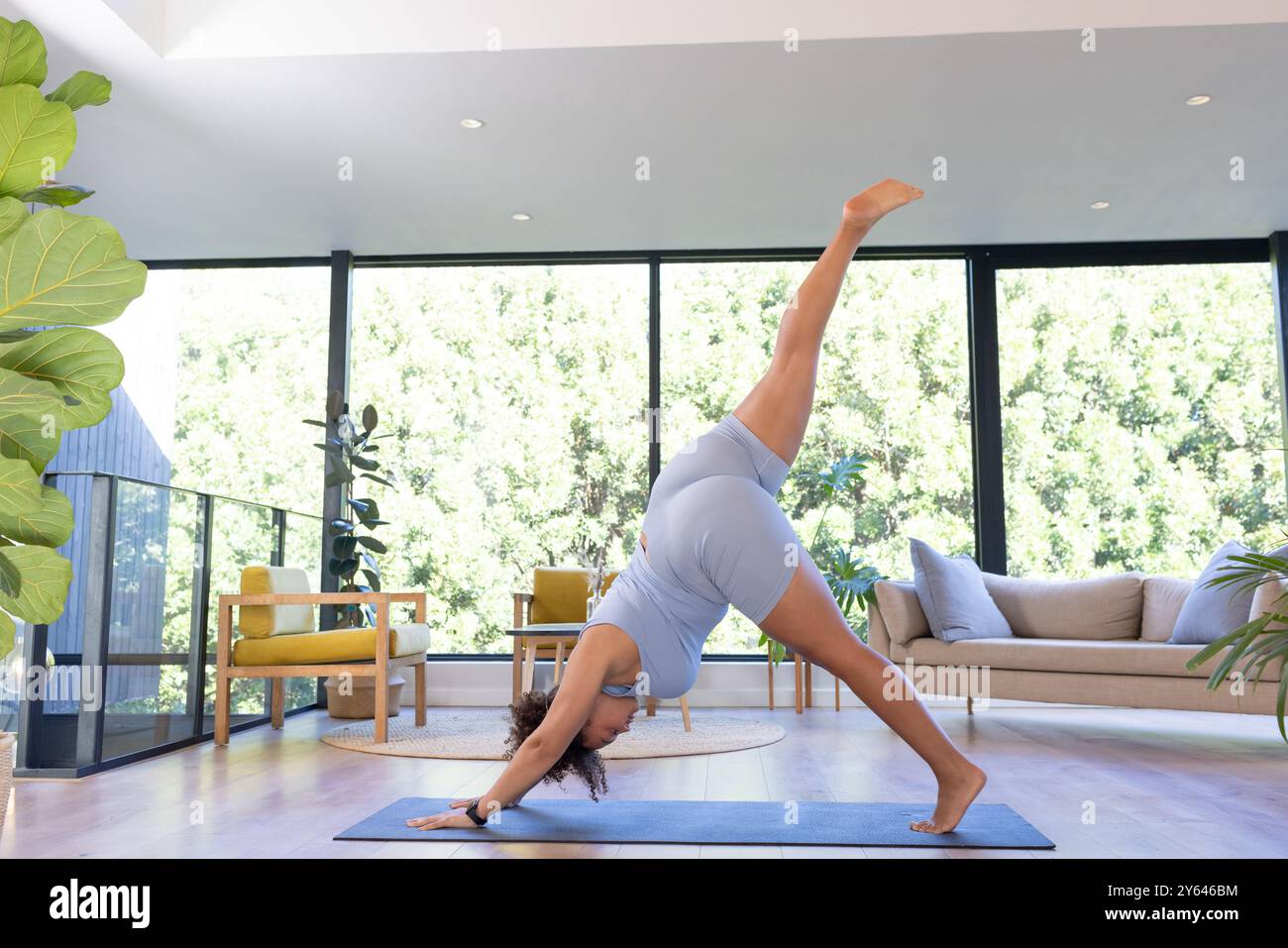 Pratica yoga, più una donna taglia che si allunga su un tappetino yoga in soggiorno, spazio fotocopie, a casa Foto Stock