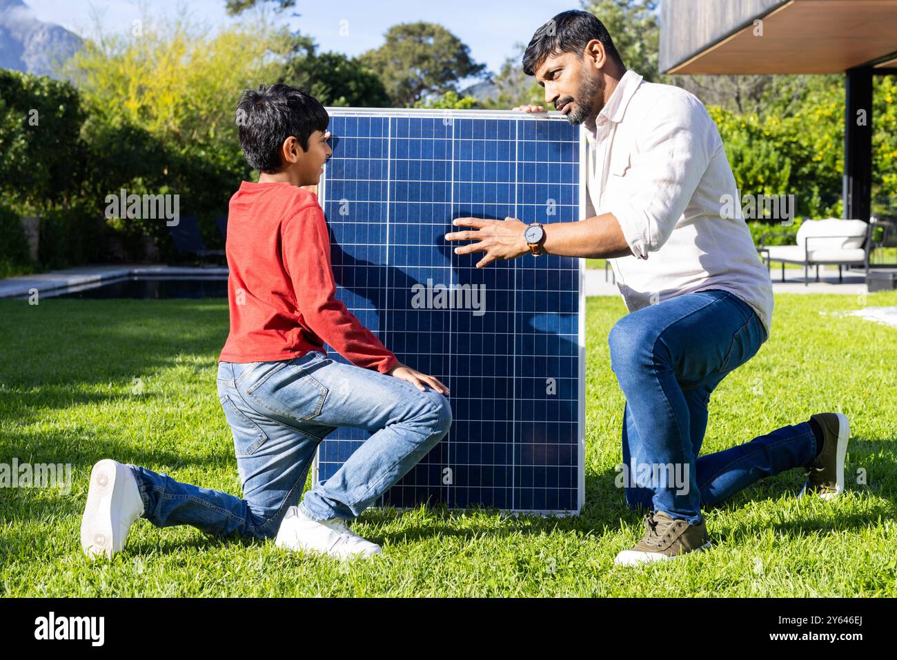 Installazione di pannelli solari in cortile, padre e figlio indiani che imparano a conoscere le energie rinnovabili Foto Stock