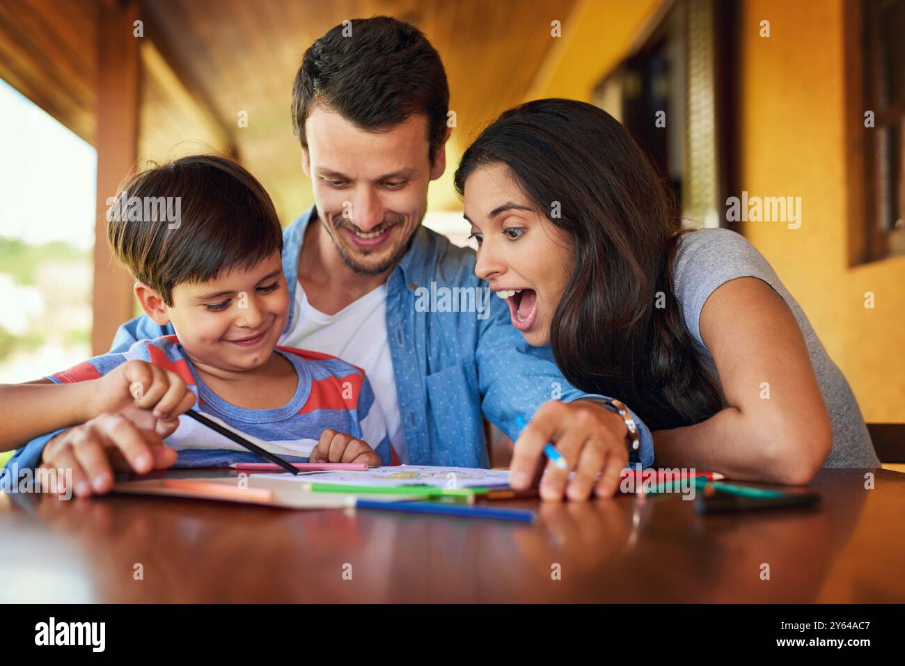 Disegnare, eccitare e fare i compiti con la famiglia a tavola per l'istruzione, il sostegno e il progetto scolastico. Apprendimento, conoscenza e sviluppo delle lezioni con i genitori Foto Stock