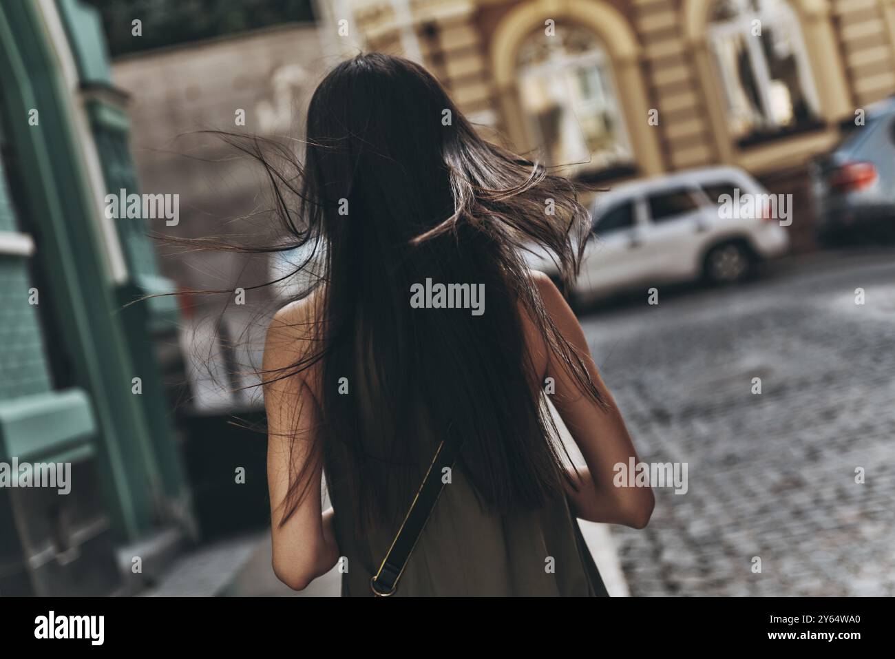 Segui il tuo sogno... Vista posteriore di una giovane donna che cammina lungo la strada mentre passa del tempo all'aperto Foto Stock