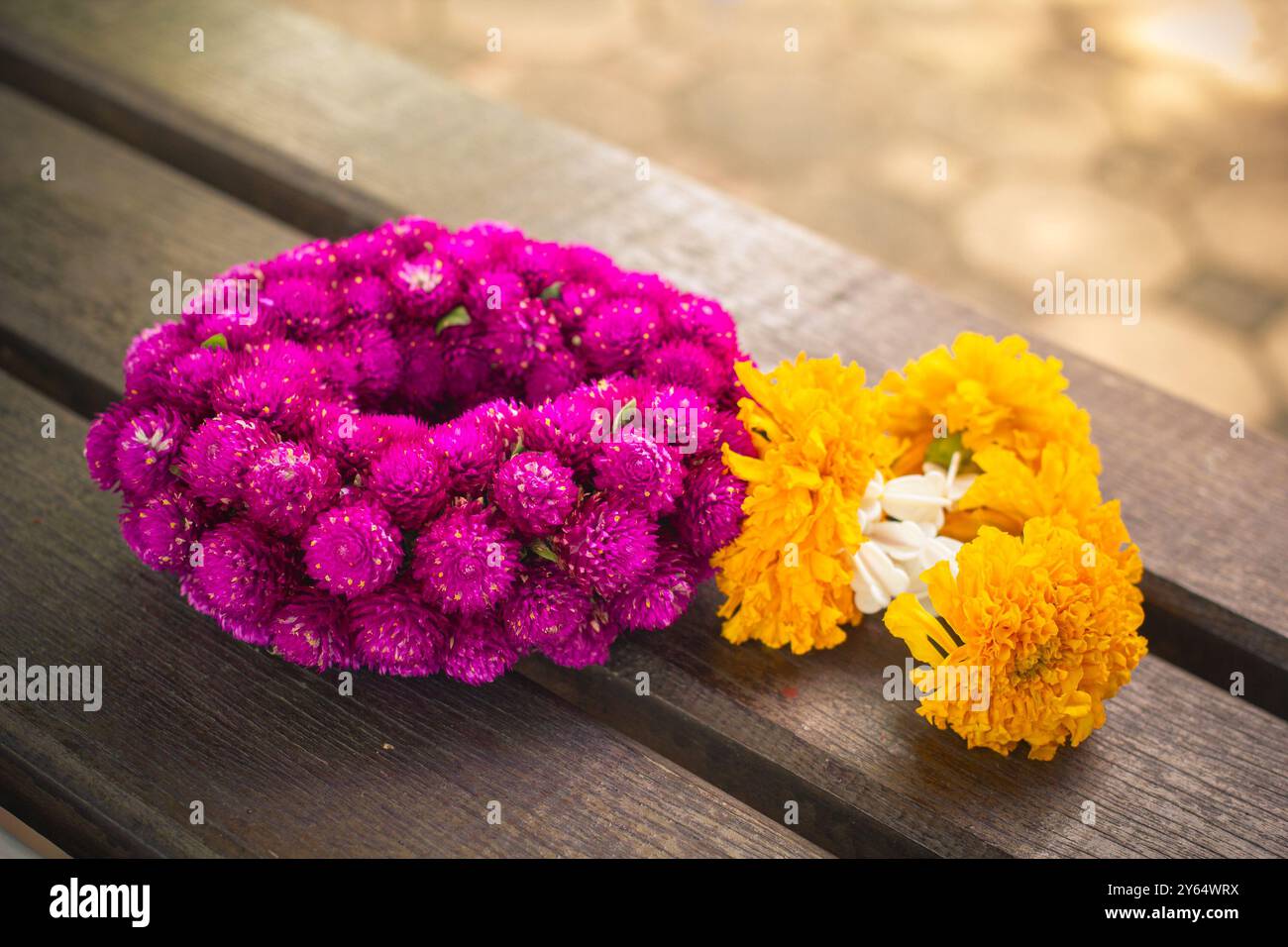 I fiori di ghirlanda consistono di calendula e globo amaranto o bottone di scapolo su sfondo in legno. Foto Stock