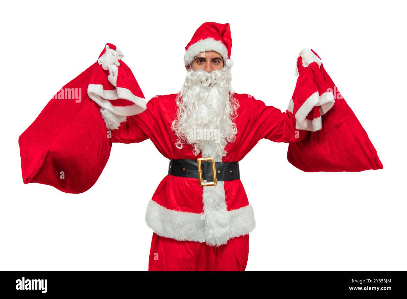 Babbo Natale sta sollevando due grandi sacchi di regali sopra la testa con un'espressione gioiosa, guardando direttamente la telecamera, incarnando lo spirito festivo Foto Stock