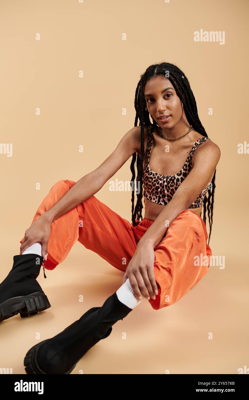 Una giovane donna sicura di sé sfoggia il suo stile unico con un outfit chic in un ambiente dalle tonalità calde. Foto Stock
