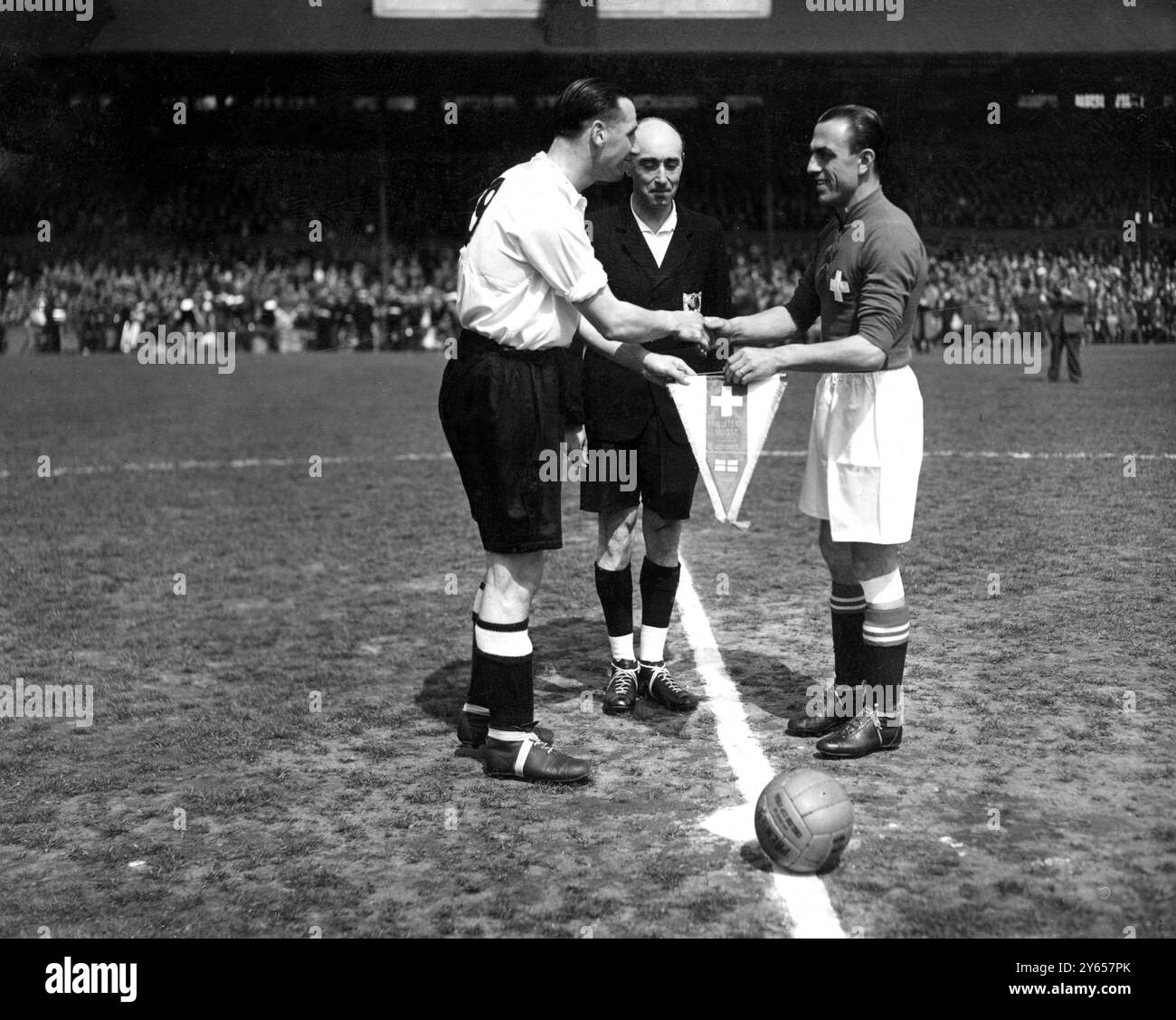 Calcio : Svizzera contro Inghilterra . Una folla di 75 , 000 spettatori allo Stamford Bridge , Londra , questo pomeriggio ha visto la partita internazionale di calcio tra Svizzera e Inghilterra . Il capitano svizzero L Amado ( a destra ) presenta una bandiera in segno della partita a Tommy Lawton , il capitano inglese . 11 maggio 1946 Foto Stock
