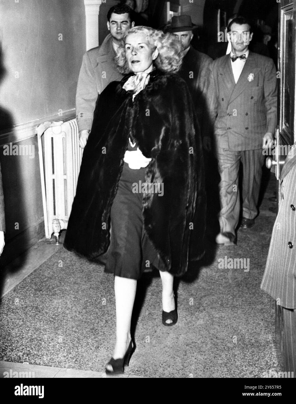 ' Axis Sally' giudicato colpevole di tradimento.......... Mildred Gillars, scortata dai vice marescialli statunitensi, lascia il tribunale distrettuale statunitense di Washington, dopo essere stata dichiarata colpevole di tradimento da una giuria della Corte federale che aveva deliberato il suo destino per più di 28 ore. ' Sally' rischia una possibile condanna da 5 anni a morte sulla sedia elettrica, anche se non ci si aspetta che la condanna a morte sia approvata. 1949 Foto Stock