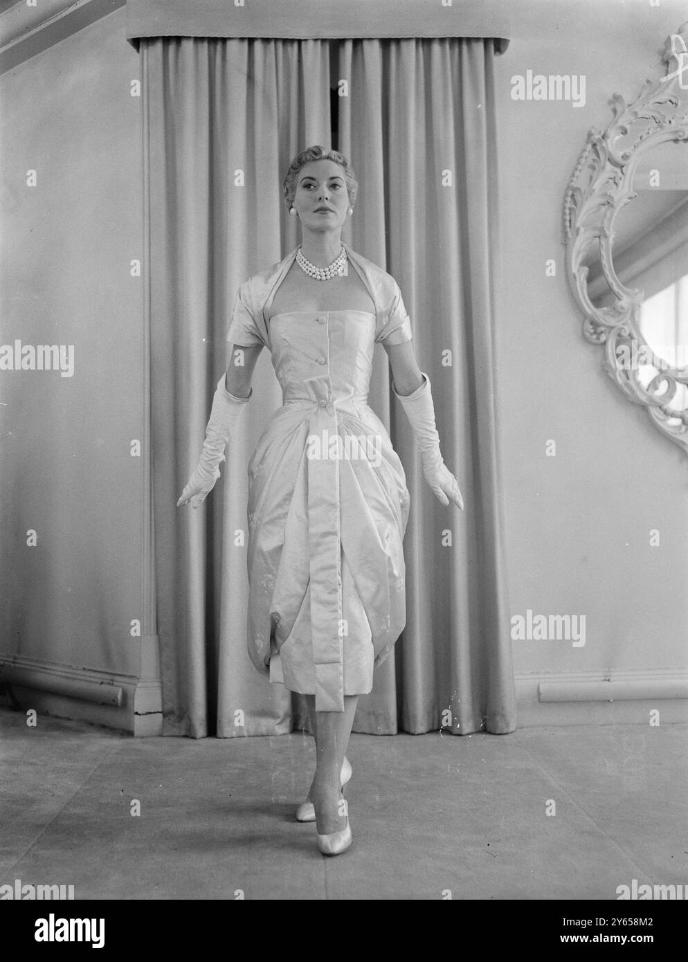 Christian Dior London ha presentato a Londra la sua collezione Winter Mid Season . Chiamato Gonconde, è un abito da sera corto in raso rosa rifinito con ricami in filo d'argento. 22 settembre 1955 Foto Stock