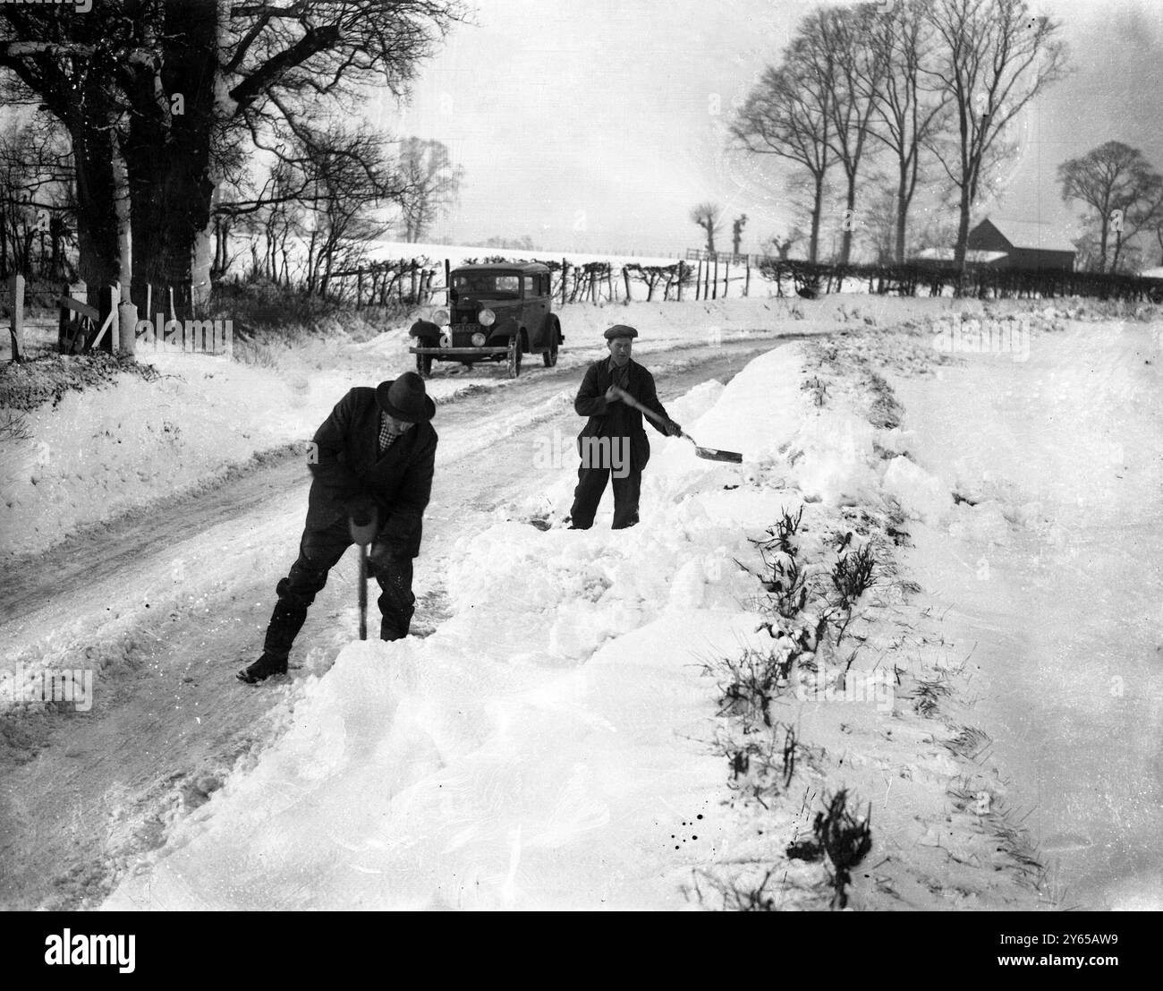 I furti di neve rallentano il traffico nell'Hertfordshire. I piedi di Snowdrifts in profondità interferiscono con il traffico sulla strada Ware-Bishops Stortford vicino all'Hertfordshire . Bande di operai stanno ripulendo la neve dalla parte superiore. Fotografie ; sgombrare la strada della neve tra Ware e Bishop 's Stortford . 27 gennaio 1937 Foto Stock