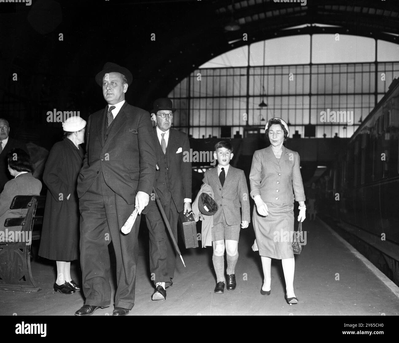 Londra , accompagnata dalla sua governante, Miss Peebles , il Principe di Galles , con il cappuccio in mano e con un gesso al ginocchio destro , arriva alla stazione di Paddington , Londra , per tornare alla Cheam School di Newbury , Berkshire , per il mandato autunnale . Il principe è stato in vacanza con la sua famiglia a Balmoral , Scozia . 22 settembre 1958 Foto Stock