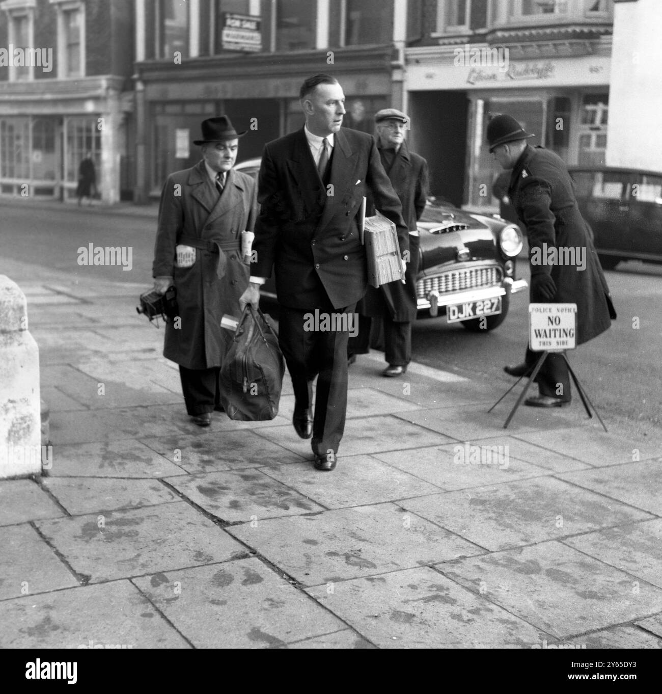 Il dottor John Bodkin Adams , accusato di omicidio della ricca vedova Edith Morrell , viene portato dinanzi alla corte dei magistrati di Eastbourne il 17 gennaio 1957 il sergente sellaro Sellars arriva alla corte portando con sé una quantità di libri da utilizzare come prova nel caso. Foto Stock