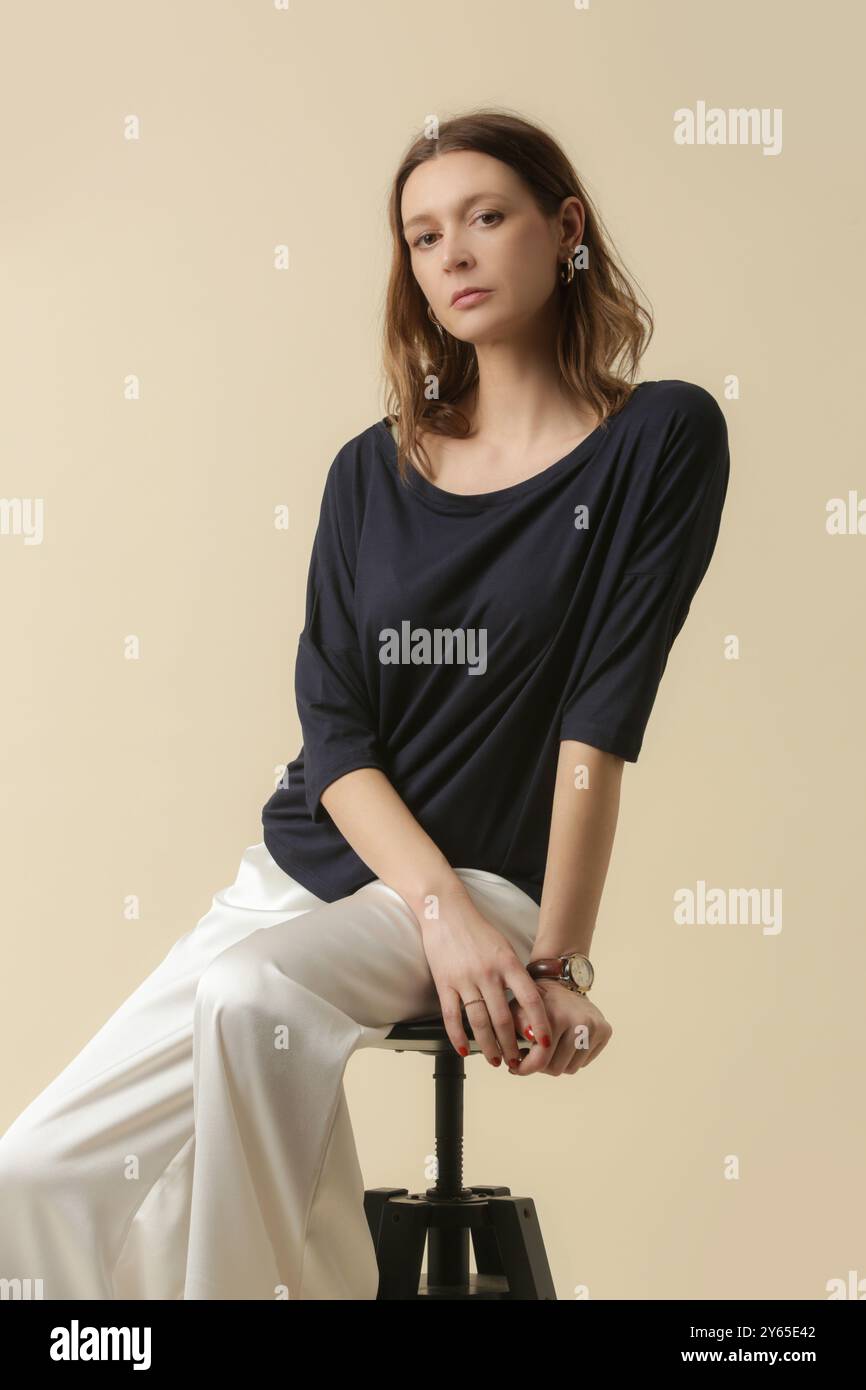 Modello femminile con top nero e pantaloni bianchi. Stile classico e semplice. Ripresa in studio. Foto Stock