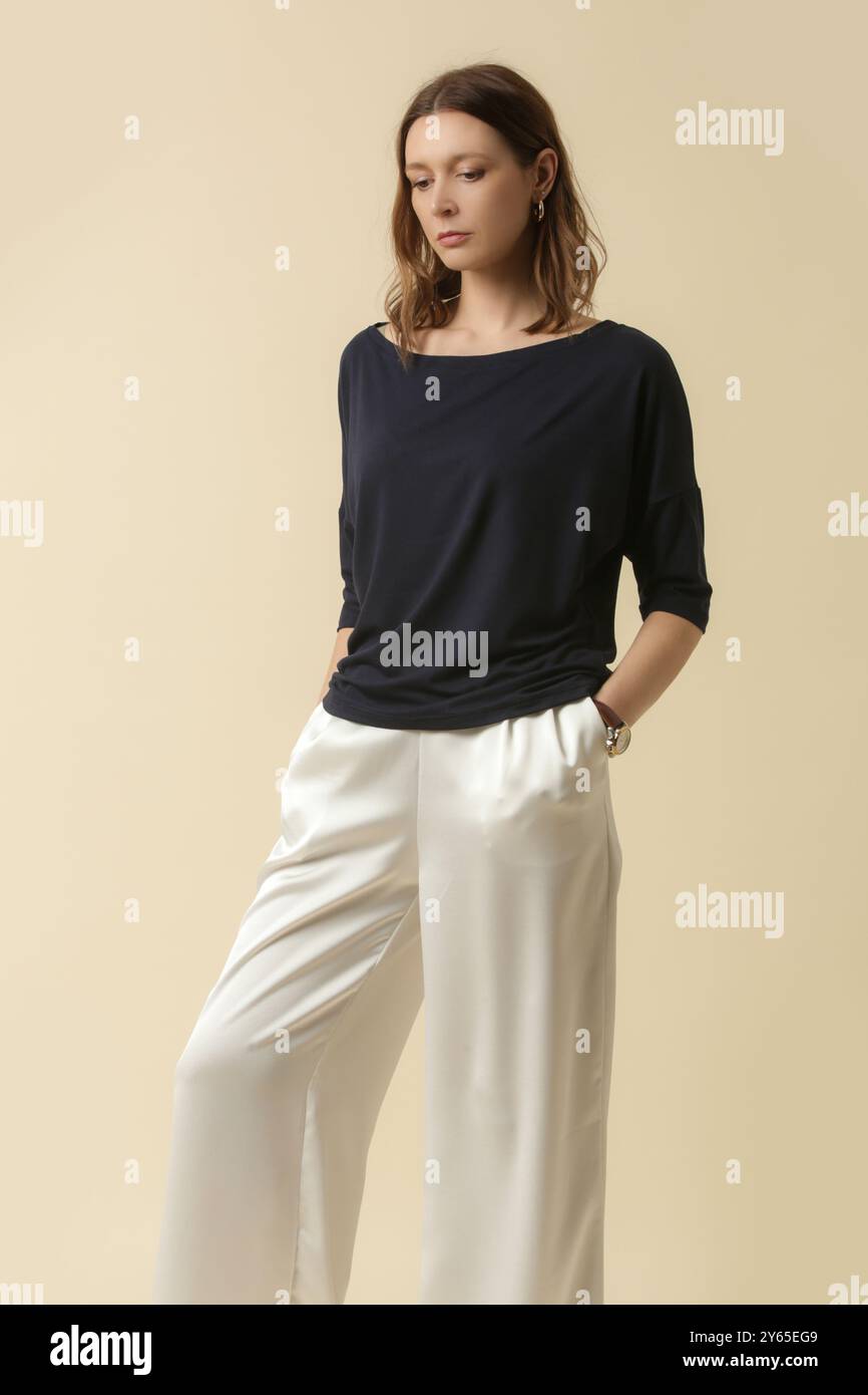Modello femminile con top nero e pantaloni bianchi. Stile classico e semplice. Ripresa in studio. Foto Stock
