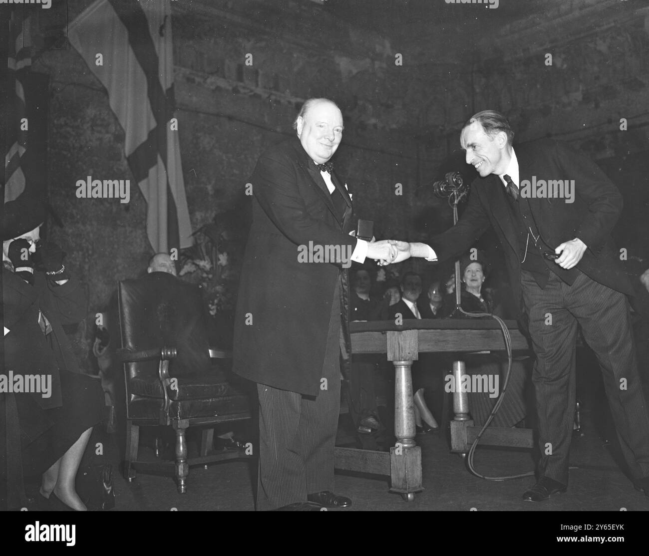 Holland Honours Mr Churchill con la presentazione della medaglia Grotius in una cerimonia tenutasi a Guildhall , Londra , presieduta dal Lord Sindaco Sir George Aylwen , Winston Churchill è stato insignito della medaglia d' oro Grotius da un rappresentante dell' equivalente olandese dell' Associazione delle Nazioni Unite , la Vereniging voor Internationale Rechtsorde . La medaglia è stata istituita nel 1925, in occasione del 300° anniversario della pubblicazione del De jure belli AC Pacis di Hugo Grotius, che ha gettato le basi del diritto internazionale. Il dottor Kappeyne Van de Coppello Right stringe la mano al signor Churchill dopo prese Foto Stock