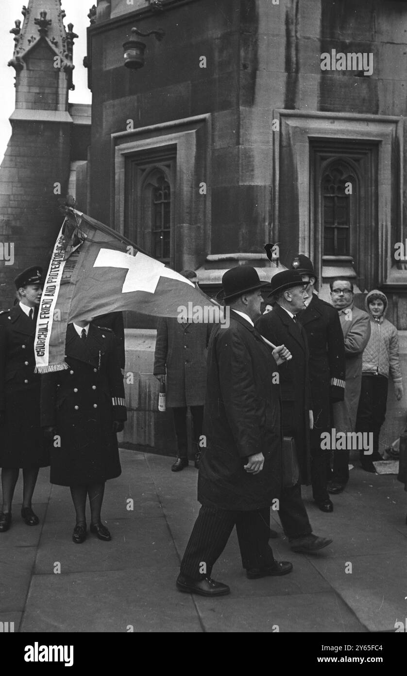 Tributo della bandiera svizzera un uomo non identificato che portava bandiera svizzera è visto vicino a Westminster Hall , dove il corpo di Sir Winston Churchill era giacente in stato prima del funerale . 27 gennaio 1965 Foto Stock