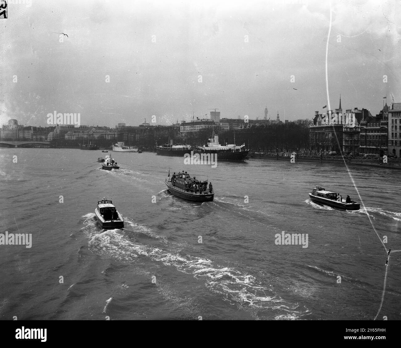 Viaggio sul Tamigi il lancio del porto di Londra l' Havengore ( centro ) , affiancato dai lanci di scorta della polizia sul Tamigi , che trasportano la bara del defunto Sir Winston Churchill , si fa strada lungo il Tamigi verso il molo di Festival Hall durante il funerale di Stato del 90enne statista . 30 gennaio 1965 Foto Stock