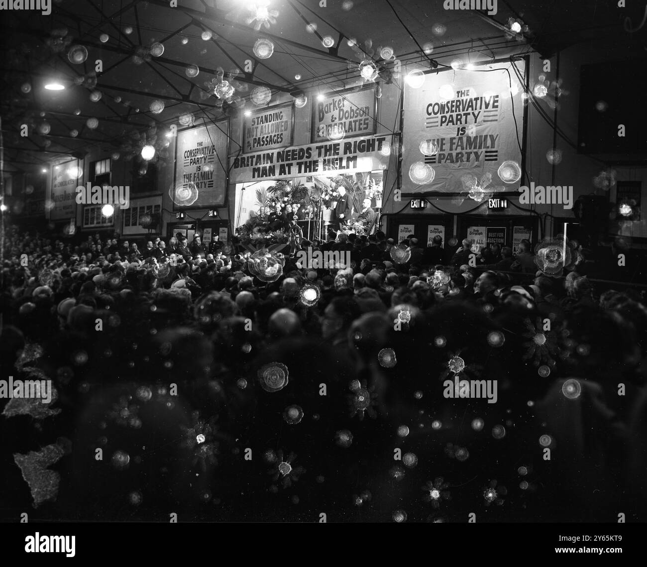 Lo skipper Churchill apre la campagna elettorale in piedi dietro la ruota di una nave e bloccato dallo slogan " la Gran Bretagna ha bisogno dell' uomo giusto al timone " , leader del partito conservatore , Winston Churchill apre la campagna elettorale generale dei Tory in un affollato stadio di Liverpool . 3 ottobre 1951 Foto Stock
