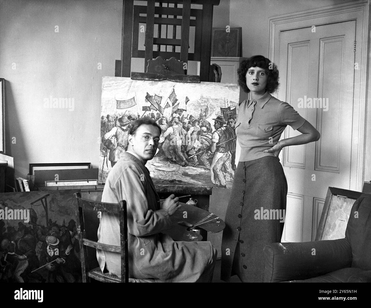 Il fidanzamento è annunciato da Michael Rothenstein, l'artista figlio di Sir William Rothenstein, che fino al suo pensionamento lo scorso luglio è stato preside del Royal College of Art per 15 anni, il signor Rothenstein, che ha 26 anni, sposerà la signorina Betty FitzGerald - anch'essa artista - la gemella della signora L FitzGerald di Londra la foto mostra il signor Michael Rothenstein al lavoro nel suo studio guardato dalla sua fidanzata Miss Betty FitzGerald il 26 settembre 1935 Foto Stock