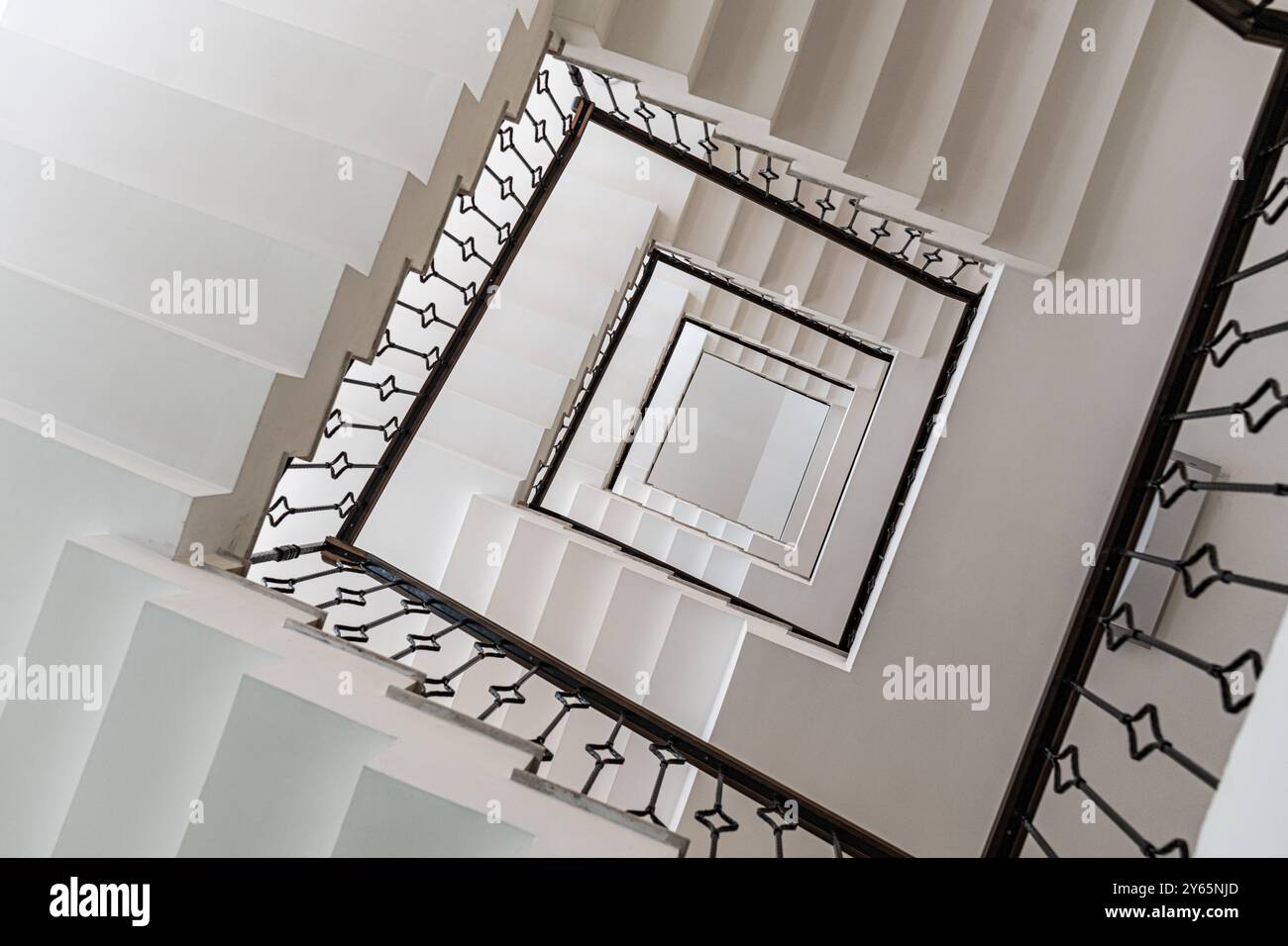 Un'affascinante ripresa verticale di una scala a spirale bianca, che enfatizza la sua eleganza geometrica e le linee pulite Foto Stock