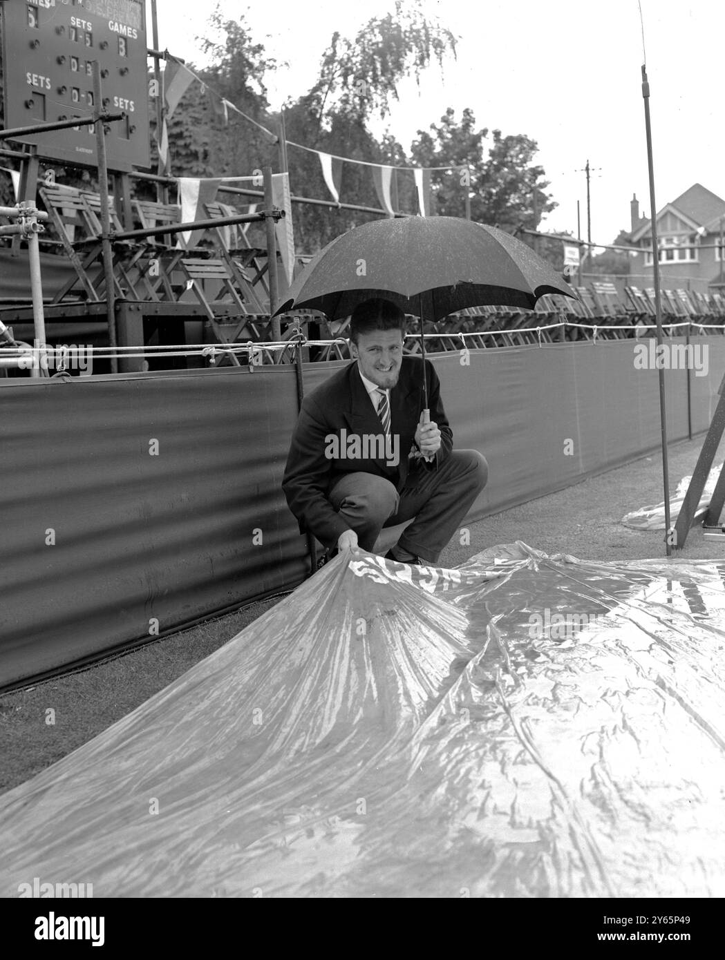 Il calciatore del Fulham Jimmy Hill sorride filosoficamente sotto la pioggia, che oggi ha smesso di giocare ai Campionati del Surrey al Surbiton ( Surrey ) Lawn Tennis Club . Il signor Hill era stato programmato per giocare nel doppio maschile. 29 maggio 1958 Foto Stock