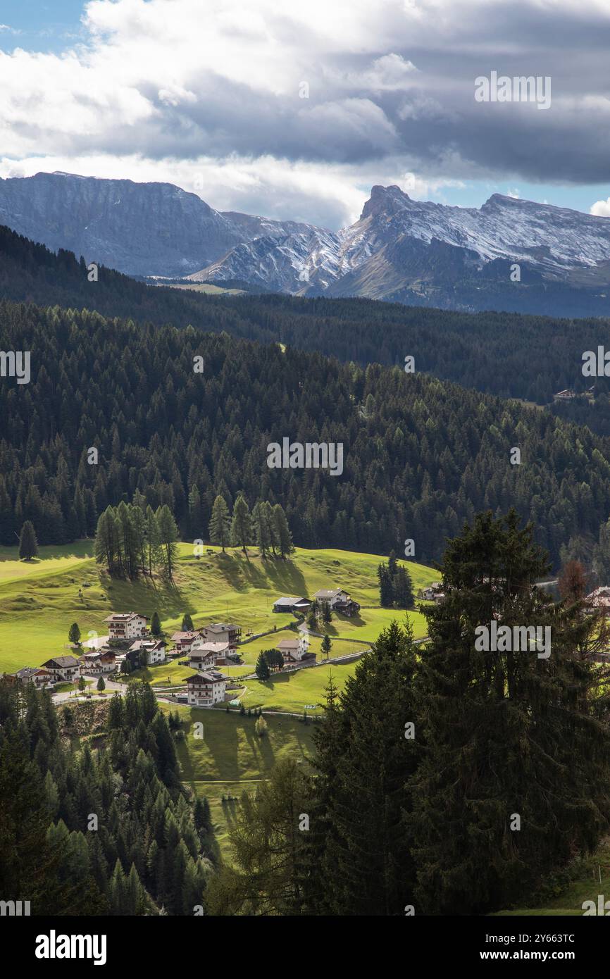 Le suggestive cime delle Dolomiti sovrastano l'affascinante villaggio alpino di Corvara, nel nord Italia, creando un contrasto mozzafiato. Foto Stock